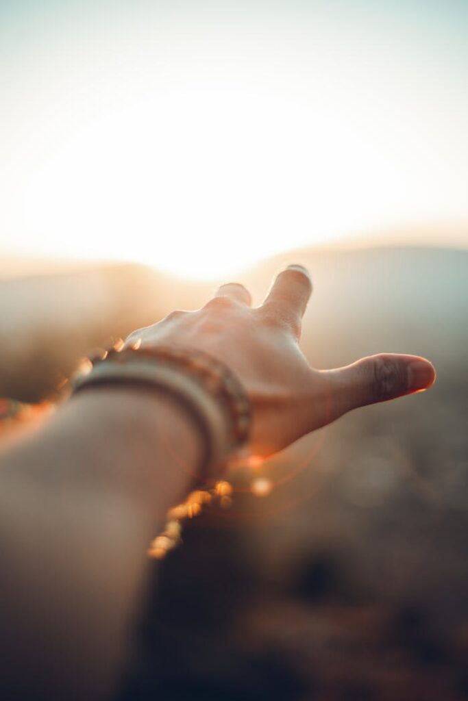 A hand adorned with bracelets reaching towards the sunlight in Beirut, capturing a vibrant moment.